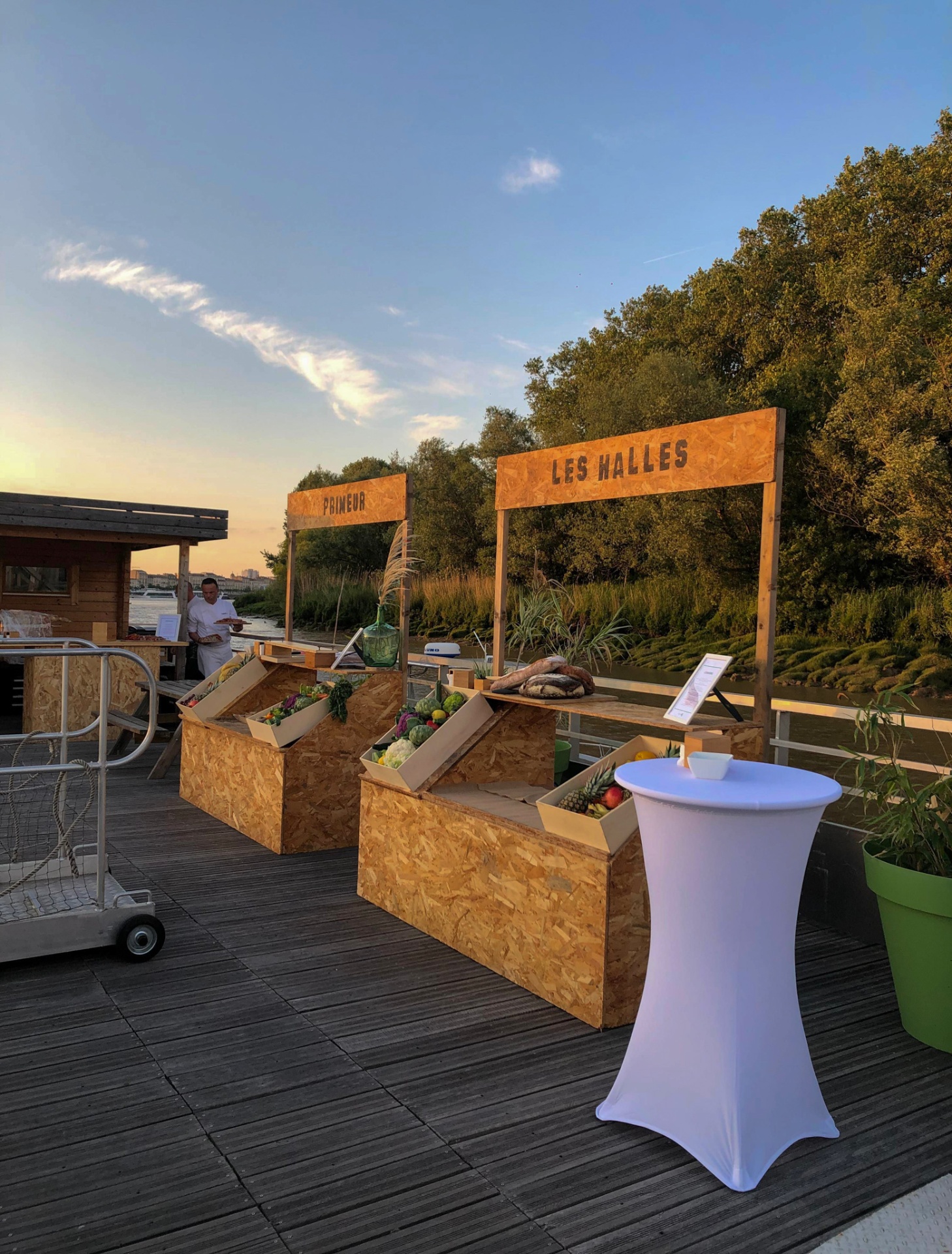 Focus sur la scénographie durable : stands en bois OSB présentant des produits du terroir lors d'une réception au bord de la Garonne. - réalisé par Agence Kulte